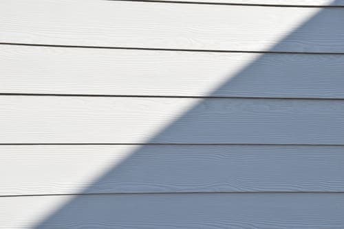 Close-up of a white wooden wall featuring a bold diagonal shadow.